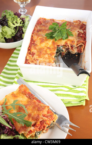 Eine Schüssel mit Spinat und Ricotta-Käse-Cannelloni mit einem grünen Salat mit einer Portion auf einen Teller. Stockfoto