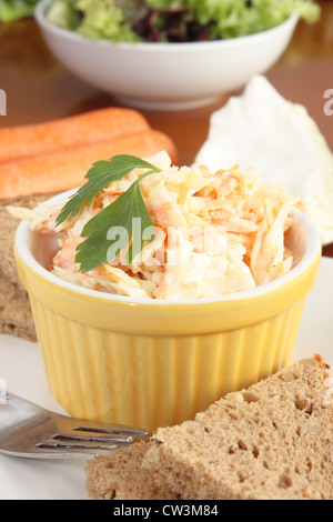 Eine Schüssel mit Krautsalat enthalten geriebenen Kohl und Karotten mit braunen oder eine ganze Mahlzeit Brot. Stockfoto