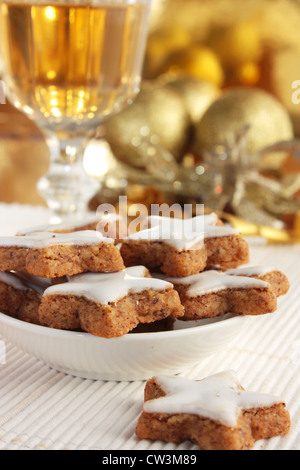 Sternförmige Zimt Plätzchen oder Kekse mit goldenen Verzierungen und einem Glas Wein oder Sherry. Stockfoto