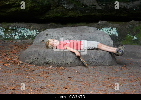 Kind blonde junge ruht auf einer Reise - liegt auf dem Stein Stockfoto