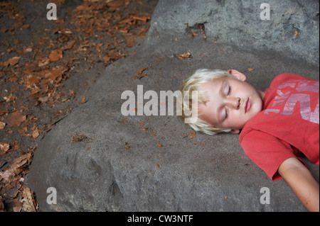 Kind blonde junge ruht auf einer Reise - liegt auf dem Stein Stockfoto