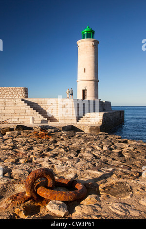 Zwei Männer zu Fuß unterhalb des Leuchtturms Cassis am Eingang zum Hafen, Cassis, Provence Frankreich Stockfoto