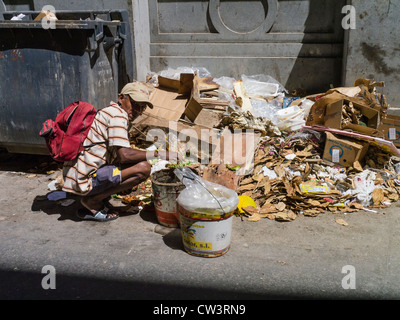 Ein kubanische Mann nimmt durch ein Haufen Müll auf der Suche nach wiederverwertbare Objekte auf der Straße in Havanna, Kuba. Stockfoto