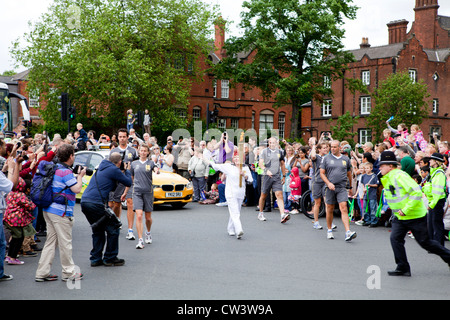 Ein olympischer Fackelträger Massen in Walsall, West Midlands als Teil der London 2012 Olympische Fackel Relais Route winken. Stockfoto