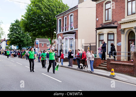 Menschenmengen säumen New Road, Willenhall, West Midlands, um die Weitergabe von die Olympische Fackel und seines Trägers vorangestellt Sponsoren erwarten Stockfoto