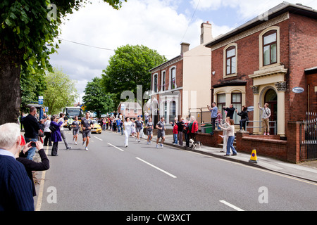 Ein olympischer Fackelträger rinnt New Road, Willenhall, West Midlands, als Teil der London 2012 Olympische Fackel Relais Route. Stockfoto