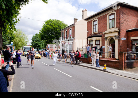 Ein olympischer Fackelträger rinnt New Road, Willenhall, West Midlands, als Teil der London 2012 Olympische Fackel Relais Route. Stockfoto