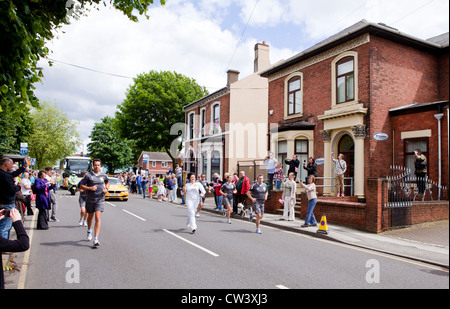 Ein olympischer Fackelträger rinnt New Road, Willenhall, West Midlands, als Teil der London 2012 Olympische Fackel Relais Route. Stockfoto