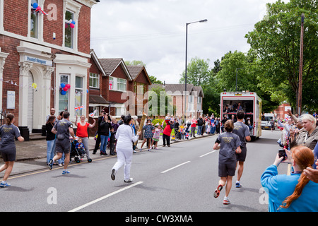 Ein olympischer Fackelträger rinnt New Road, Willenhall, West Midlands, als Teil der London 2012 Olympische Fackel Relais Route. Stockfoto