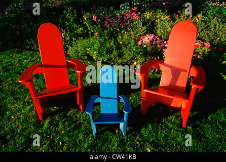 Diese sind hölzerne Gartenmöbel gefärbt. Es gibt zwei große rote Stühle und einen kleinen blauen Stuhl zwischen zwei großen. Sie Stockfoto