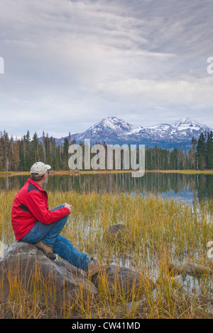 Mann sitzt auf einem Felsen am See, Scott-See, drei Schwestern, Willamette National Forest, Oregon, USA Stockfoto