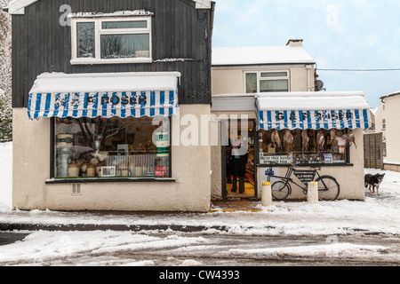 Dorf Metzgerei im Schnee in Gloucestershire mit Lieferung Bicyvcle draußen. Stockfoto