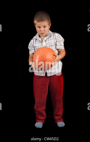 Junge hält Halloweens orange Kürbis Foto auf dem schwarzen Hintergrund Stockfoto