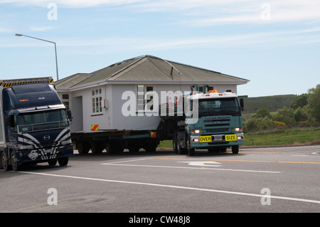 Manchmal ganze Häuser bewegen sich auf dem Weg durch Neuseeland.  Auf Den Straßen Neuseelands ist Ein frühneuzeitliche Haus Unterwegs. Stockfoto