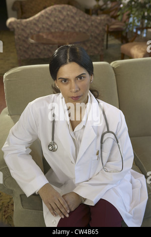 Porträt von einer Ärztin, die auf einer Couch sitzend Stockfoto