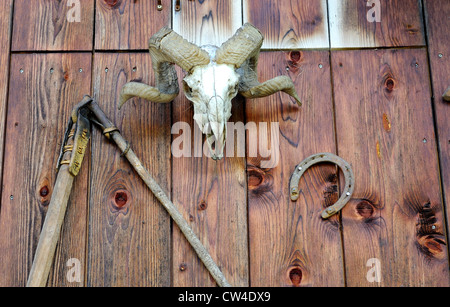 Alte Werkzeuge für die Holzbearbeitung und landwirtschaftliche Geräte fest an der Seite einer hölzernen Scheune in den österreichischen Alpen. Stockfoto