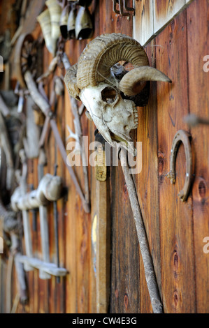 Alte Werkzeuge für die Holzbearbeitung und landwirtschaftliche Geräte fest an der Seite einer hölzernen Scheune in den österreichischen Alpen. Stockfoto