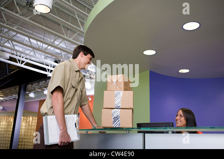 Angestellte an der Rezeption erhalten eine Paket aus einer Lieferung Mann Stockfoto