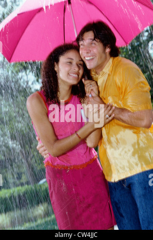 Junges Paar im Regen stehen mit einem Regenschirm Stockfoto