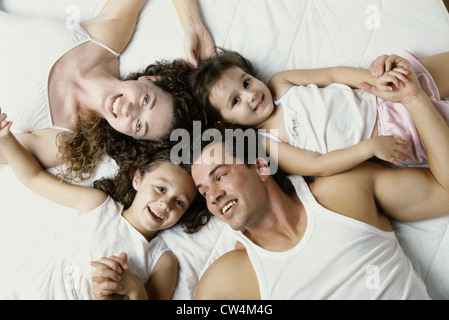 Erhöhte Ansicht der Eltern mit ihren zwei Töchtern auf dem Bett liegend Stockfoto