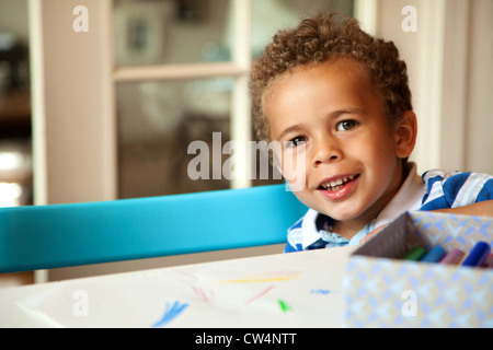 Lächelnd afroamerikanischen jungen auf einem Stuhl sitzend und immer bereit für seine Lektion Stockfoto