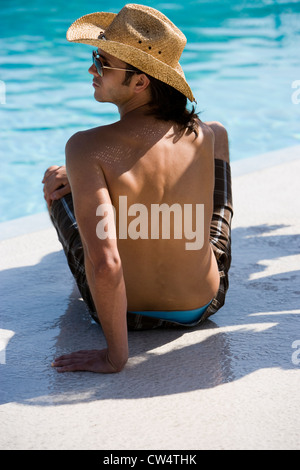 Rückansicht eines jungen Mannes sitzen am Rand des Swimming pool Stockfoto