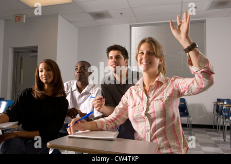 Studenten, die Teilnahme an Vortrag während einer Frau Hand hob im Klassenzimmer Stockfoto