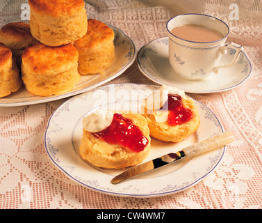 Britische Creme Tee. Tasse Tee mit Milch und Teller mit Gebäck, Sahne und Marmelade. Stockfoto
