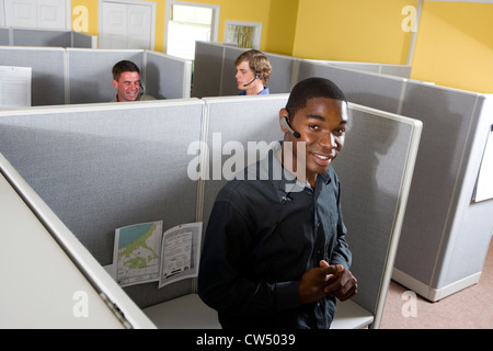 Porträt eines Geschäftsmannes gelehnt Desk während Kollegen unterhalten sich in den Hintergrund Stockfoto