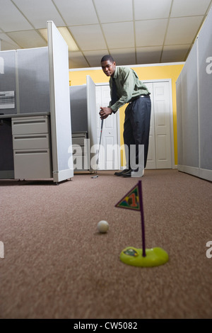 Junger Mann in einem Büro Golf zu spielen Stockfoto