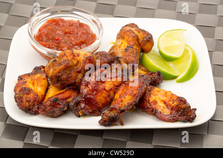 Hähnchenflügel mit Tomaten-Dip und Limette garnieren - Studio gedreht Stockfoto