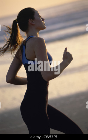 Seitenansicht einer jungen Frau, die am Strand joggen Stockfoto