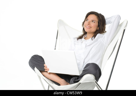 Junge Frau sitzt auf einem Stuhl und hält einen laptop Stockfoto