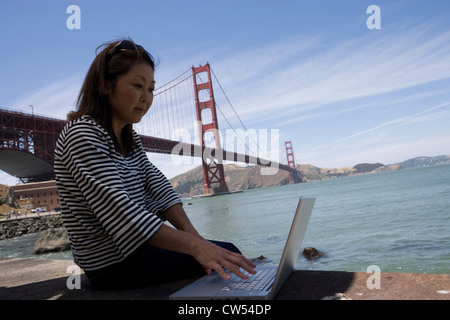 Reife Frau mit einem Laptop mit einer Hängebrücke in den Hintergrund, Golden Gate Bridge, San Francisco, Kalifornien, USA Stockfoto