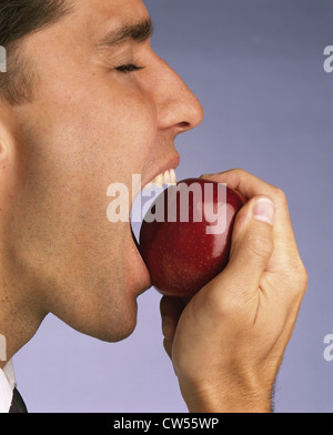 Nahaufnahme eines jungen Mannes, der einen Apfel beißen Stockfoto