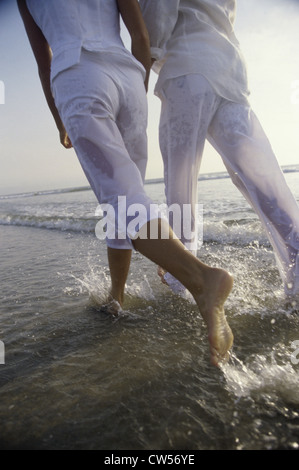 Rückansicht des jungen Paares zu Fuß am Strand Stockfoto