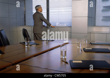 Rückansicht eines Geschäftsmannes aus einem Fenster in einem Sitzungssaal Stockfoto