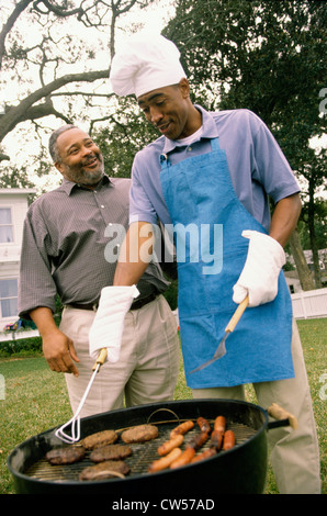 Junger Mann mit seinem Vater neben ihm stehenden Grillen Stockfoto