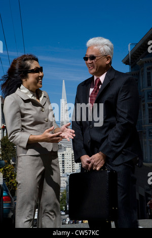 Unternehmer im Gespräch mit einer Geschäftsfrau und lächelnd, San Francisco, Kalifornien, USA Stockfoto