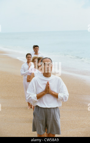 Gruppe von Menschen, die meditieren am Strand Stockfoto