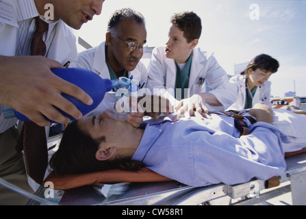 Gruppe von Ärzten, die Wiederbelebung eines Mannes auf einer Trage liegend Stockfoto