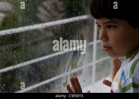 Nahaufnahme eines jungen Blick aus dem Fenster an einem regnerischen Tag Stockfoto