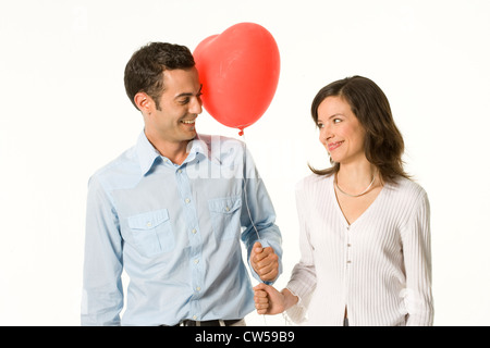 Junges Paar hält einen Herz-Form-Ballon und sahen einander Stockfoto