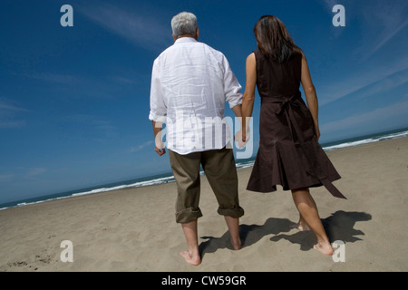 Rückansicht des ein älteres paar Hand in Hand am Strand Stockfoto