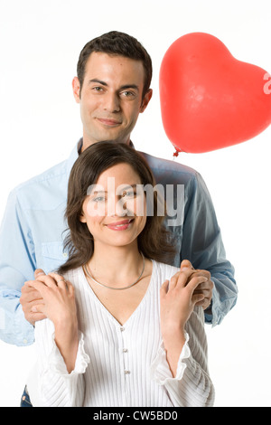 Porträt eines jungen Paares lächelnd mit einer Herz-Form-Ballon hinter Ihnen Stockfoto