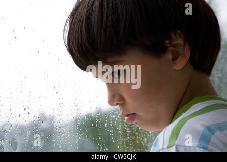 Nahaufnahme eines jungen Blick aus dem Fenster an einem regnerischen Tag Stockfoto