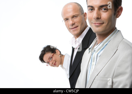 Zwei Geschäftsleute lächelnd mit einer Geschäftsfrau spähen hinter Ihnen Stockfoto
