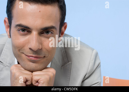 Porträt eines Geschäftsmannes, der mit seinen Händen an seinem Kinn lächelnd Stockfoto