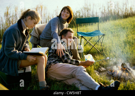 Eltern und ihre Tochter in der Nähe ein Lagerfeuer sitzen Stockfoto