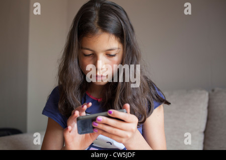 Junges Mädchen spielt auf dem Handy zu Hause Stockfoto